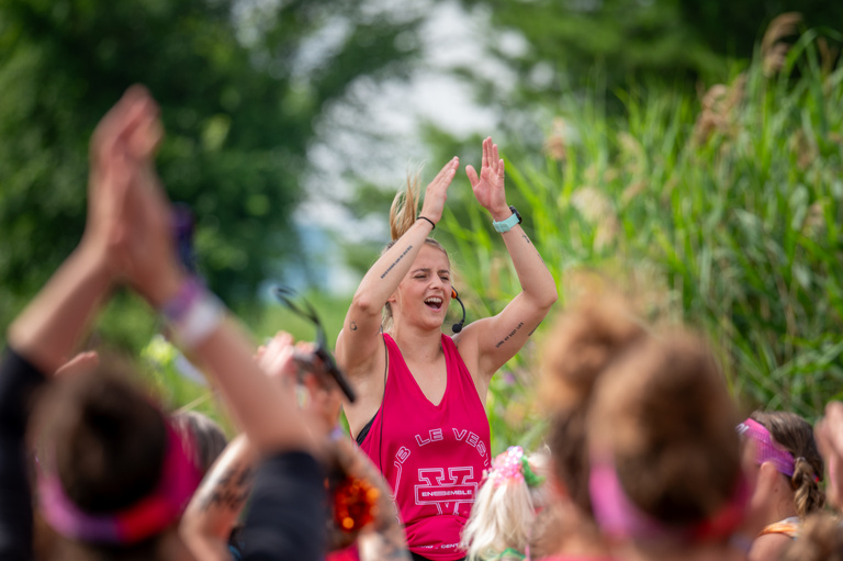 A participant raises her arms among other racers at an outdoor event.