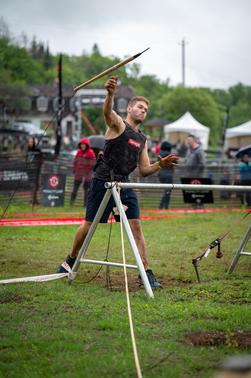 An athlete prepares to throw a spear on an outdoor obstacle course.