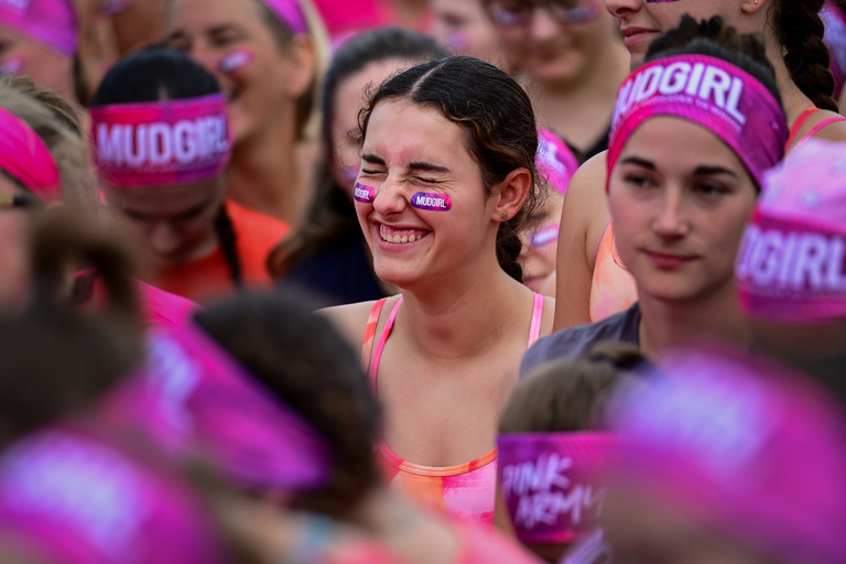 Smiling participants gather in a crowd before an outdoor obstacle race.